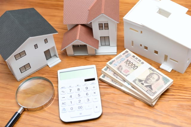 家の模型と電卓と現金
